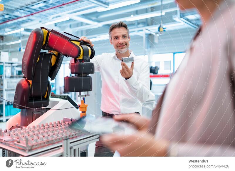 Businessman showing workpiece to businesswoman in a modern factory hall human human being human beings humans person persons caucasian appearance