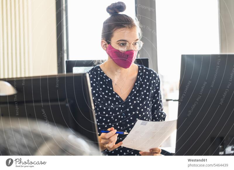 Businesswoman wearing face mask working on computer while sitting at office color image colour image indoors indoor shot indoor shots interior interior view