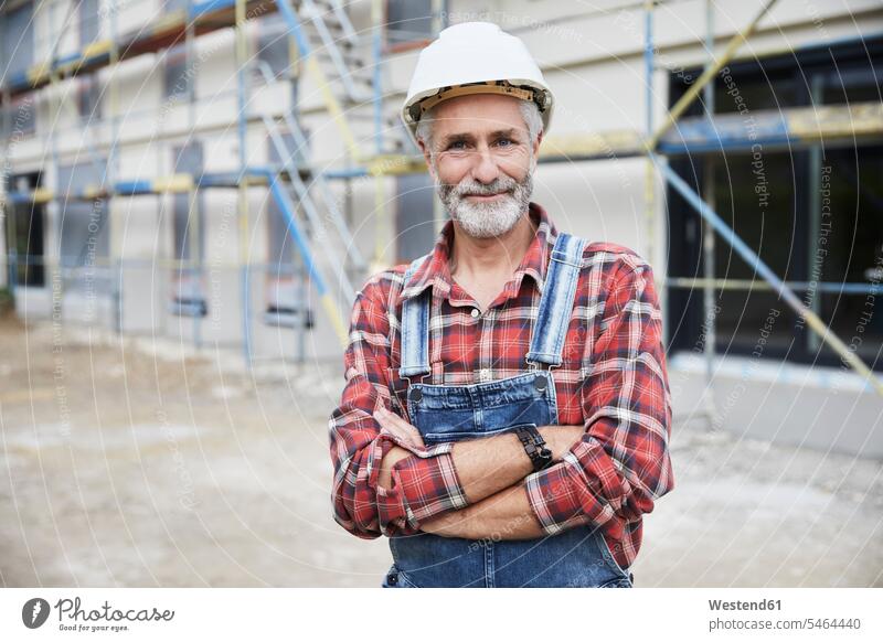 Smiling construction worker with crossed arms at construction site human human being human beings humans person persons caucasian appearance caucasian ethnicity