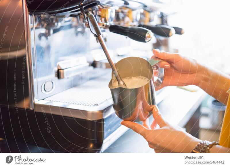Hands of female barista frothing milk with espresso machine in coffee shop color image colour image indoors indoor shot indoor shots interior interior view