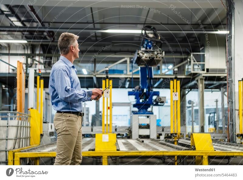 Male supervisor with digital tablet looking at manufacturing equipment in industry color image colour image indoors indoor shot indoor shots interior