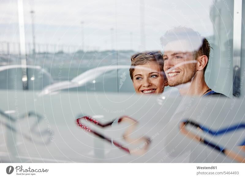 Portrait of smiling couple at the airport looking out of window windows portrait portraits view seeing viewing smile twosomes partnership couples terminal
