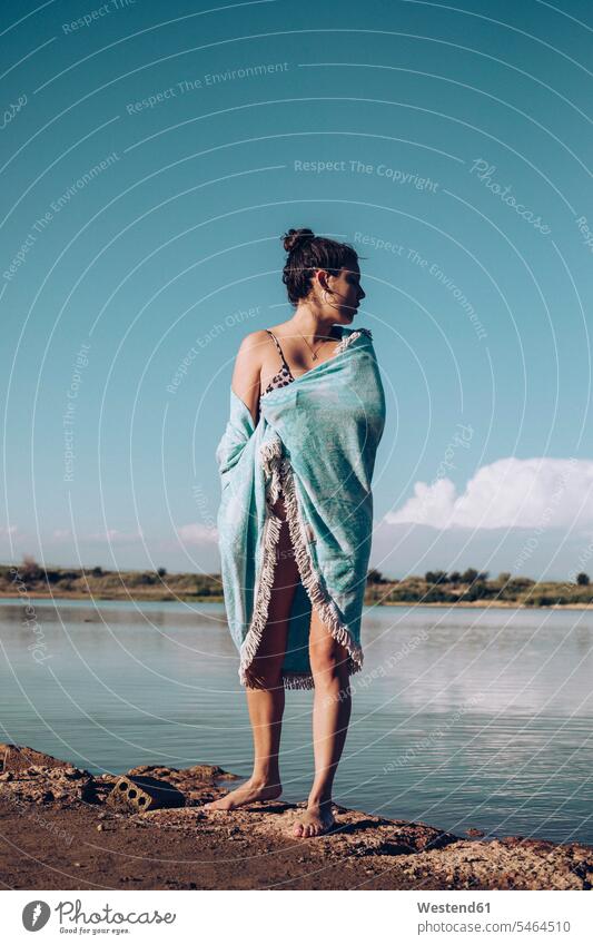 Young woman wrapped in a towel standing at lakeshore human human being human beings humans person persons caucasian appearance caucasian ethnicity european 1