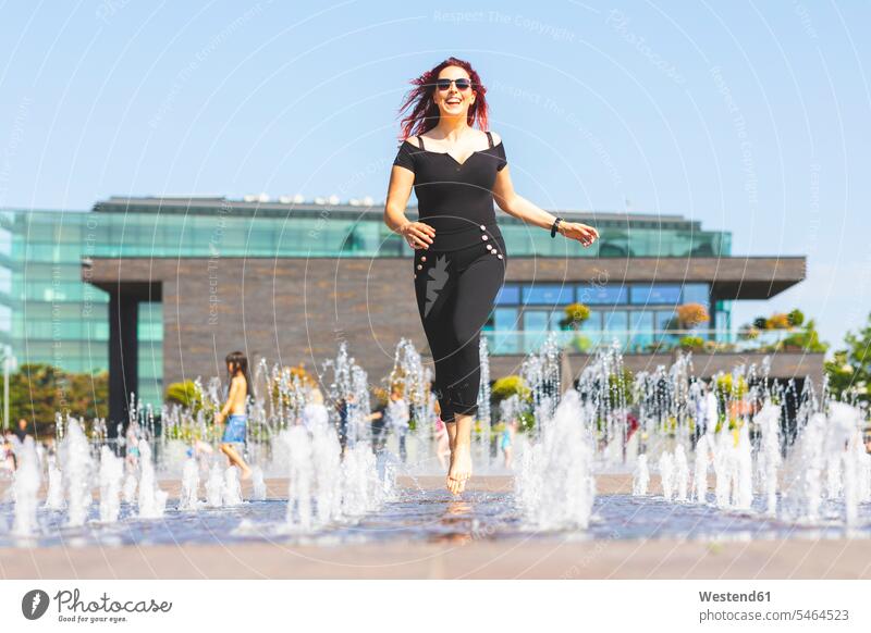 Young woman having fun running through a fountain fountains Fun funny females women Adults grown-ups grownups adult people persons human being humans