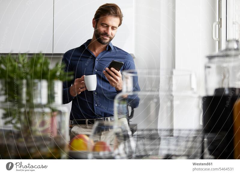 Businessman using mobile phone while drinking coffee at cafeteria color image colour image indoors indoor shot indoor shots interior interior view Interiors day