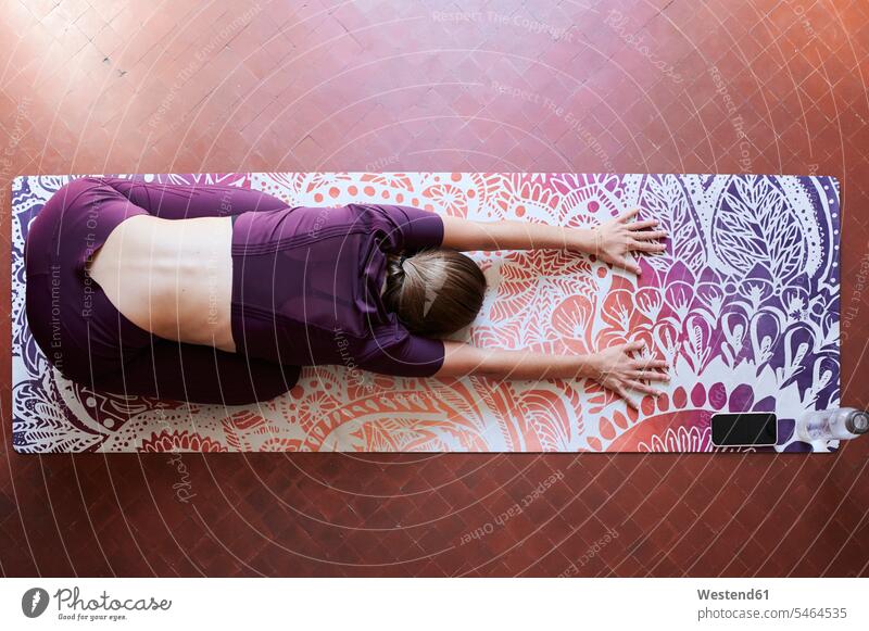 Young brunette woman practising yoga in student dorm, child position from above telecommunication phones telephone telephones cell phone cell phones Cellphone