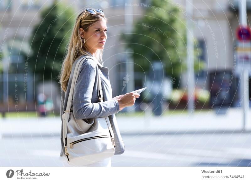 Young businesswoman working with digital tablet while standing with suitcase in the street business life business world business person businesspeople