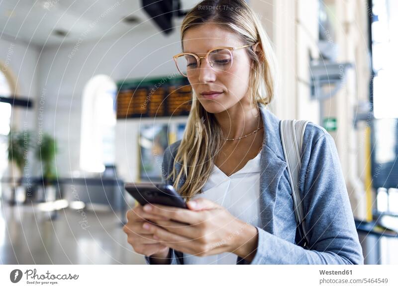 Young woman texting with her mobile phone in the train station hall business life business world business person businesspeople business woman business women