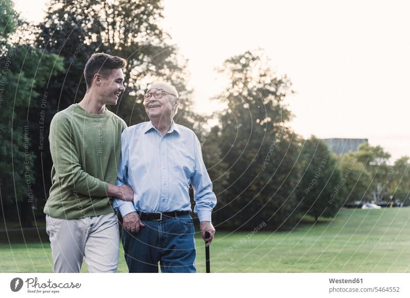 Young man assisting his grandfather walking in a park human human being human beings humans person persons caucasian appearance caucasian ethnicity european 2