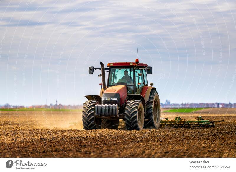 Farmer in tractor plowing field in spring agriculturist agriculturists farmers motor vehicles road vehicle road vehicles tractors drive seasons spring season