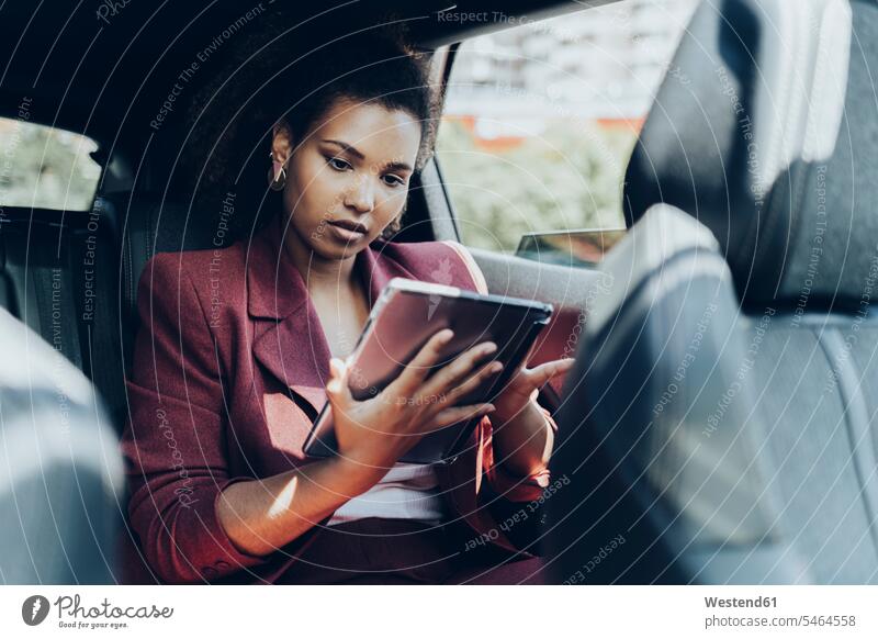 Young female entrepreneur using digital tablet while sitting in car color image colour image Spain Vehicle Interior day daylight shot daylight shots day shots