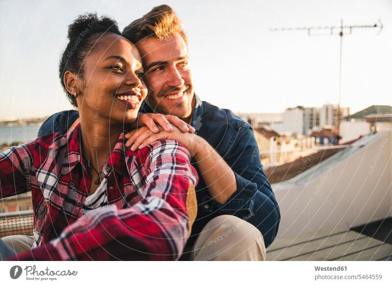 Happy affectionate young couple sitting on rooftop in the evening human human being human beings humans person persons African black black ethnicity coloured