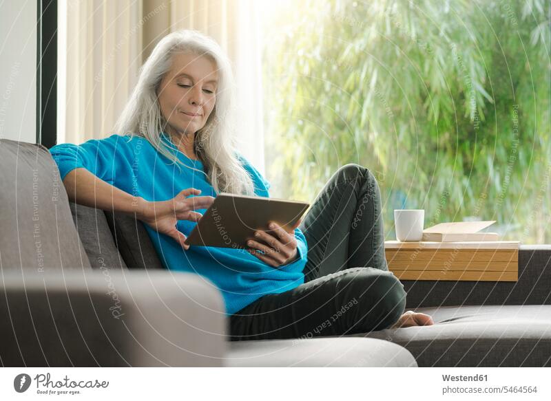 Portrait of mature woman sitting on the couch at home using digital tablet digitizer Tablet Computer Tablet PC Tablet Computers iPad Digital Tablet