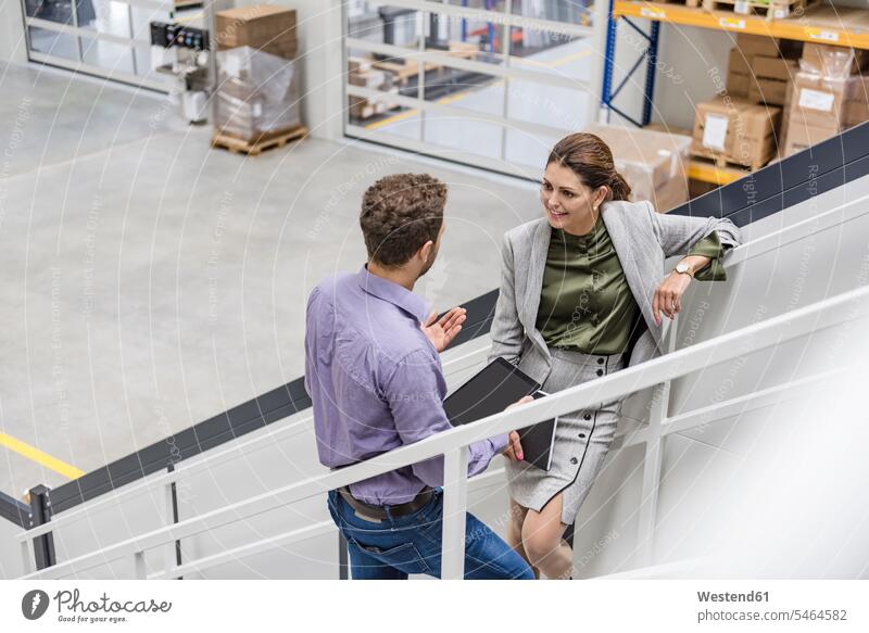 Busenessman and woman standing on stairs in company, talking conversations stairway businesswoman businesswomen business woman business women Businessman