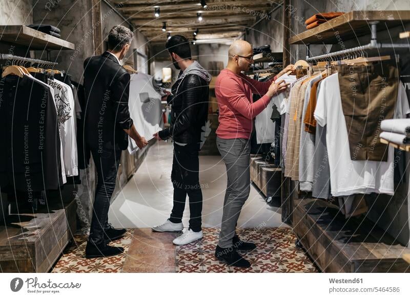 Three men in modern menswear shop with new collection customer clientele clients customers men's fashion Showing show man males contemporary people persons