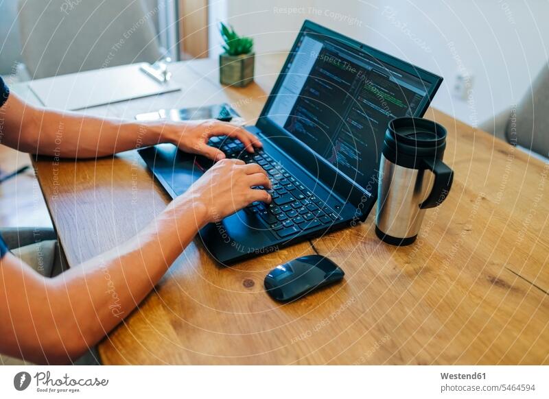 Male web designer programming through on laptop at desk in office color image colour image indoors indoor shot indoor shots interior interior view Interiors day