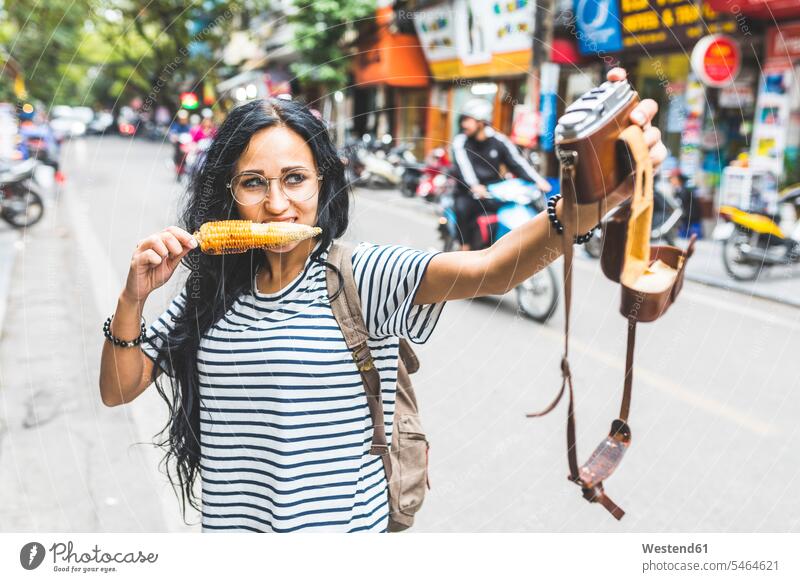 Vietnam, Hanoi, young woman taking a selfie with old-fashioned camera on the street eating a corn cob portrait portraits corncob corn cobs Corn On The Cob Corns