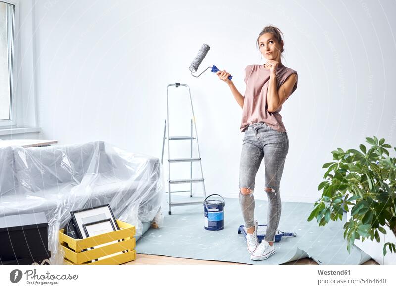 Thoughtful woman with head in hands holding paint roller while standing at home color image colour image indoors indoor shot indoor shots interior interior view