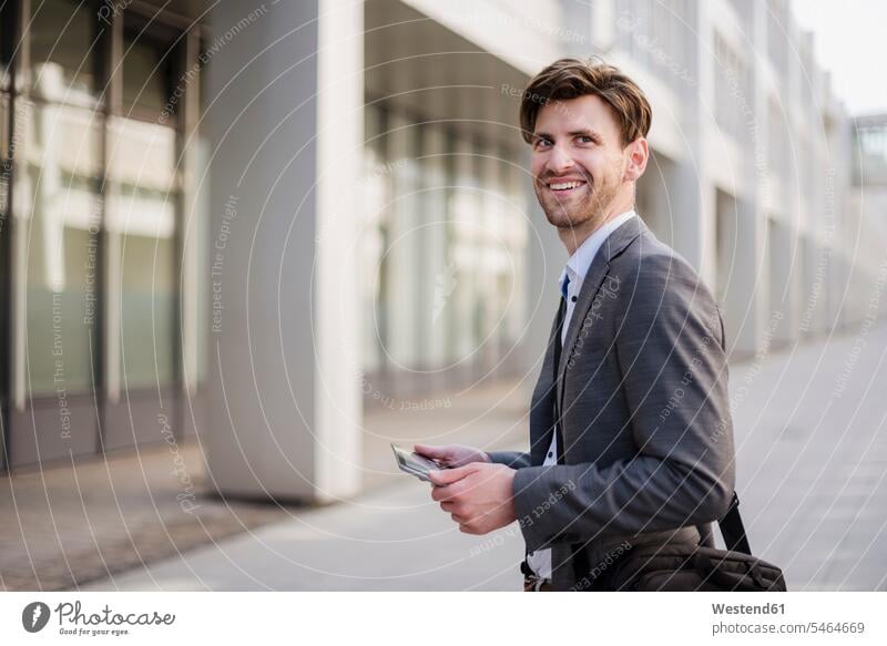 Smiling businessman in the city with bag and tablet Businessman Business man Businessmen Business men digitizer Tablet Computer Tablet PC Tablet Computers iPad