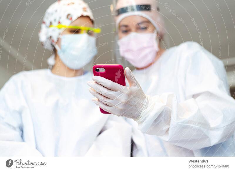 Dentist showing mobile phone to assistant while standing at office color image colour image indoors indoor shot indoor shots interior interior view Interiors