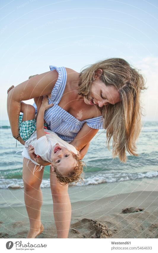 Mother playing with son while standing at beach color image colour image outdoors location shots outdoor shot outdoor shots sunset sunsets sundown atmosphere