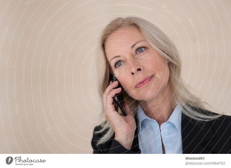Close-up of female entrepreneur talking over mobile phone against wall in office color image colour image Germany indoors indoor shot indoor shots interior