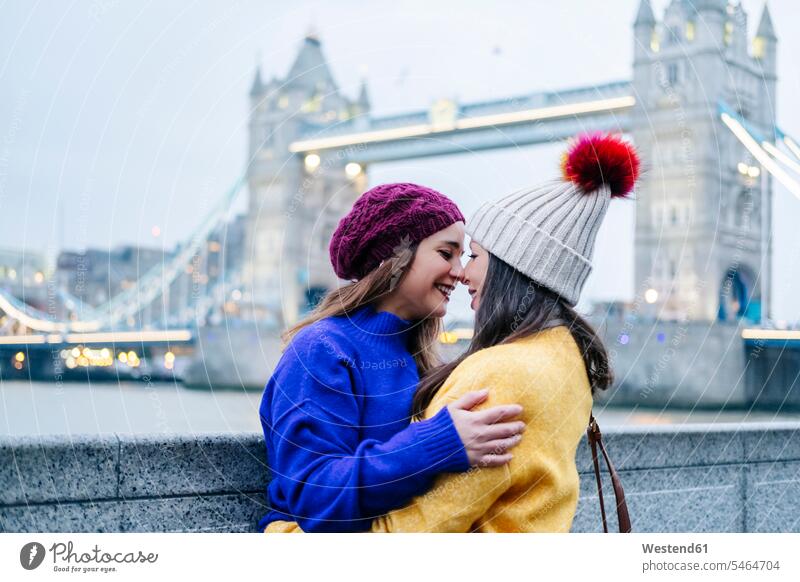 London, United Kingdom. A couple of two girls embracing in front of Tower Bridge image picture pictures images photograph photos photographs horizontal