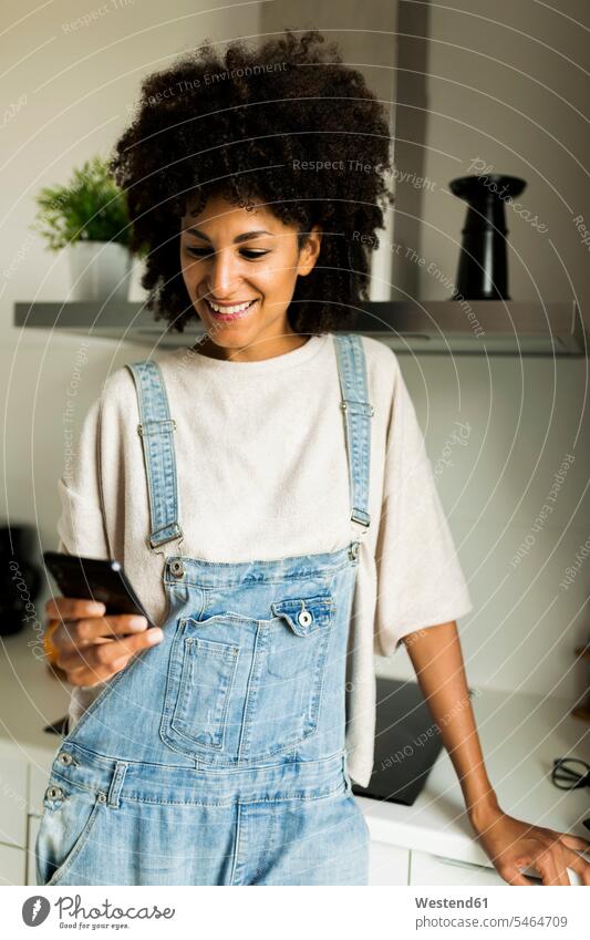 Smiling woman using cell phone in kitchen at home mobile phone mobiles mobile phones Cellphone cell phones smiling smile females women telephones communication