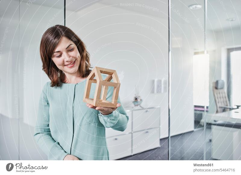 Smiling young businesswoman looking at architectural model in office portrait portraits Architectural Model offices office room office rooms businesswomen