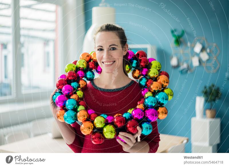 Portrait of smiling woman with colourful Christmas bauble wreath colorful X-Mas yule Xmas X mas smile females women Christmas wreath Christmas wreaths