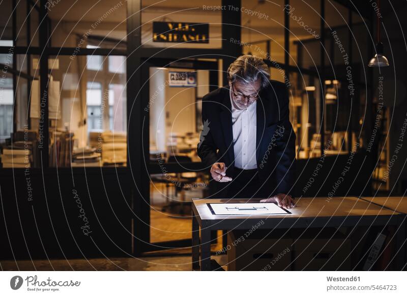 Senior businessman looking at shining tablet in office human human being human beings humans person persons caucasian appearance caucasian ethnicity european 1