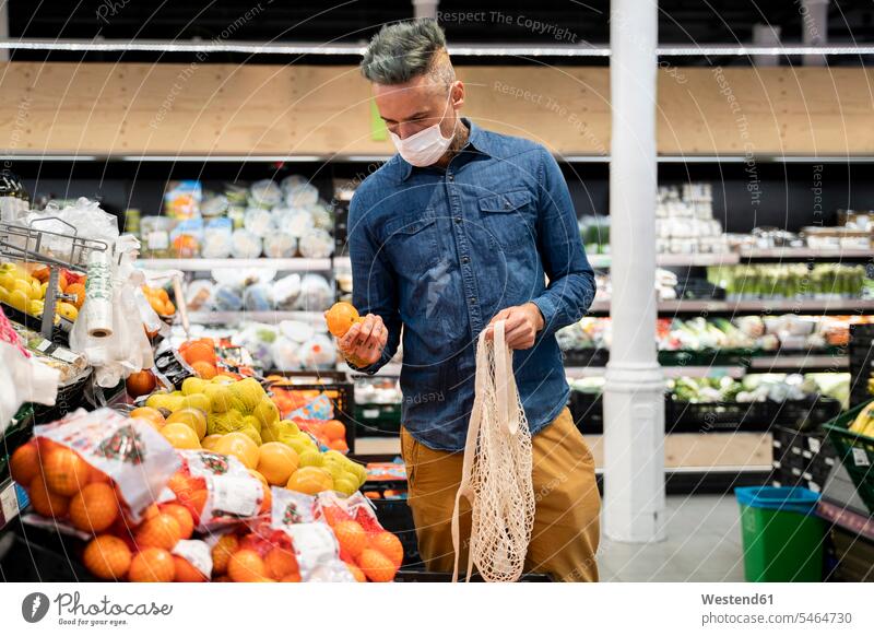 Man wearing face mask buying fruits in supermarket color image colour image Spain casual clothing casual wear leisure wear casual clothes Casual Attire indoors