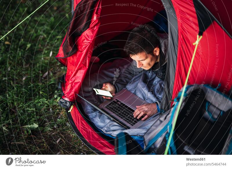 Man camping in Estonia, sitting in tent, using laptop Laptop Computers laptops notebook tents nature natural world computer computers journey travelling
