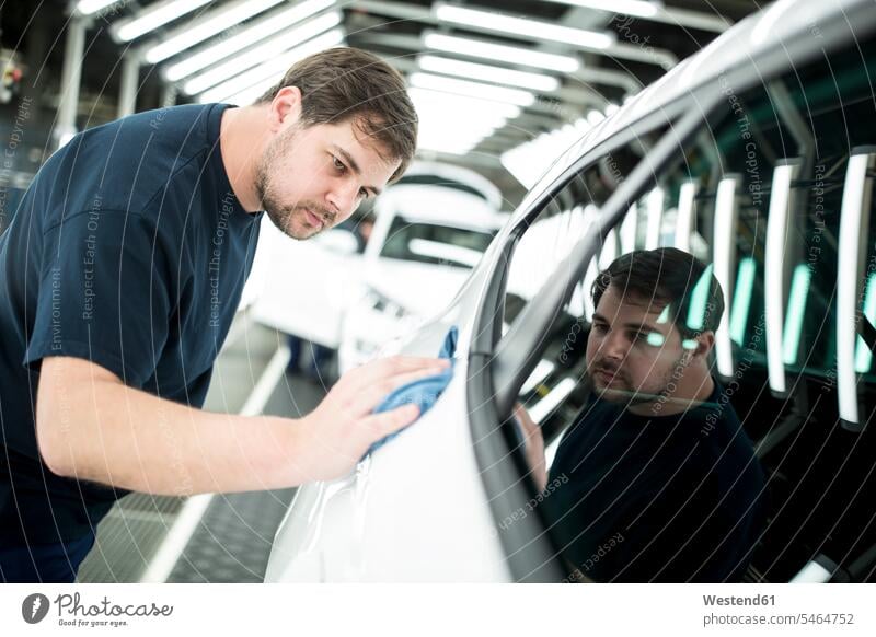 Man working in modern car factory wiping finished car Occupation Work job jobs profession professional occupation blue collar blue collar worker