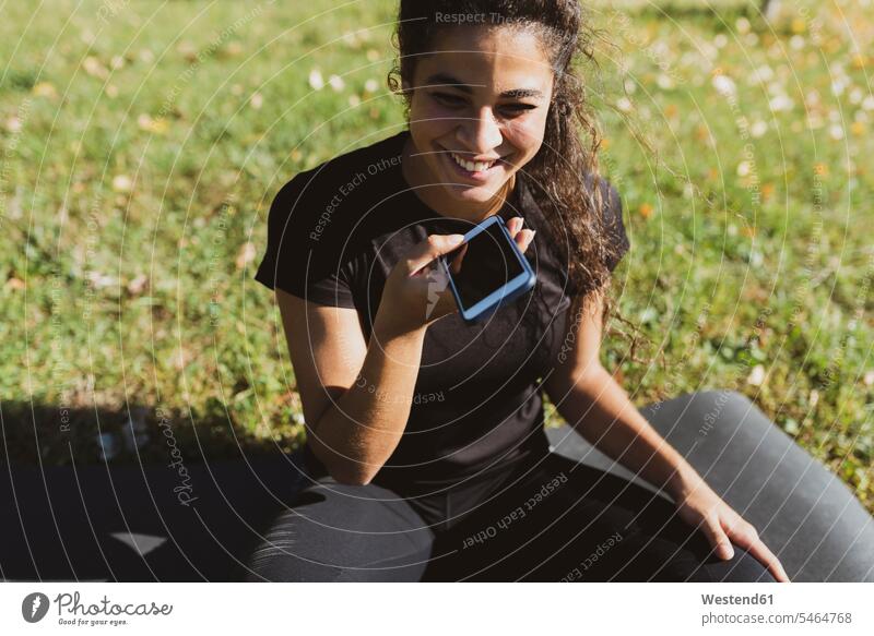 Happy sporty young woman having a break on a meadow using cell phone meadows sportive sporting athletic mobile phone mobiles mobile phones Cellphone cell phones