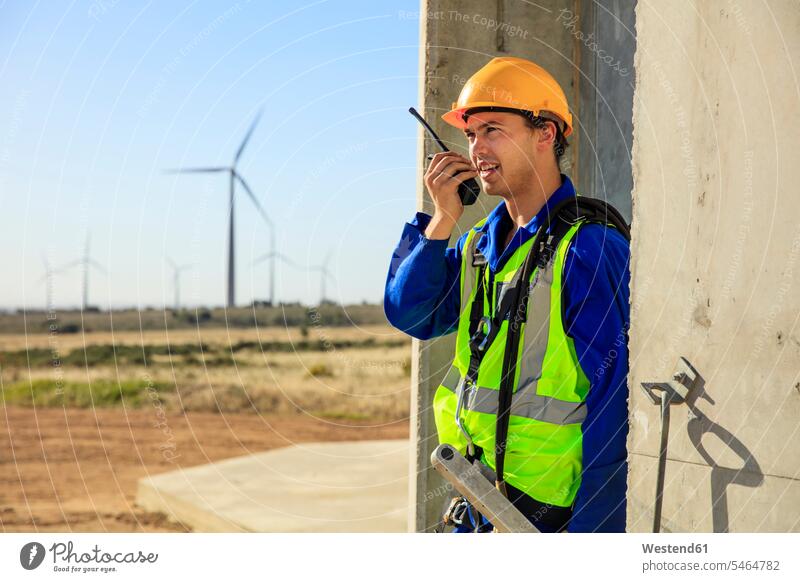 Technician using walkie-talkie at wind turbine wind turbines walkie talkie walkie-talkies walkie talkies two-way radios technician technicians wind energy