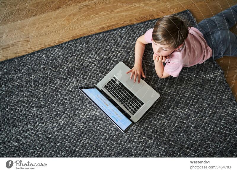Boy lying on floor, working on laptop computers Laptop Computer Laptop Computers laptops notebook carpets rug rugs learn laying down lie lying down at home