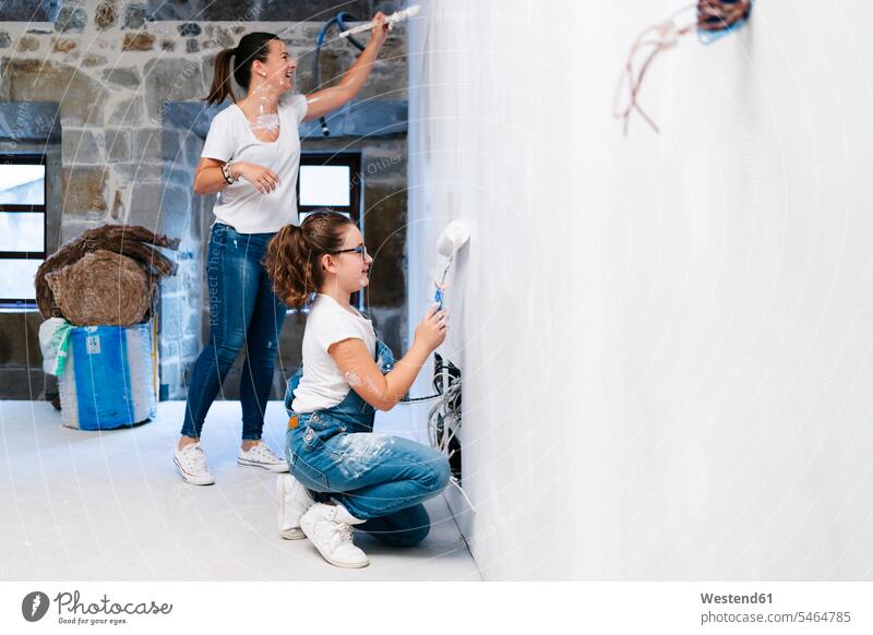 Mother and daughter painting a wall of her new house together human human being human beings humans person persons caucasian appearance caucasian ethnicity