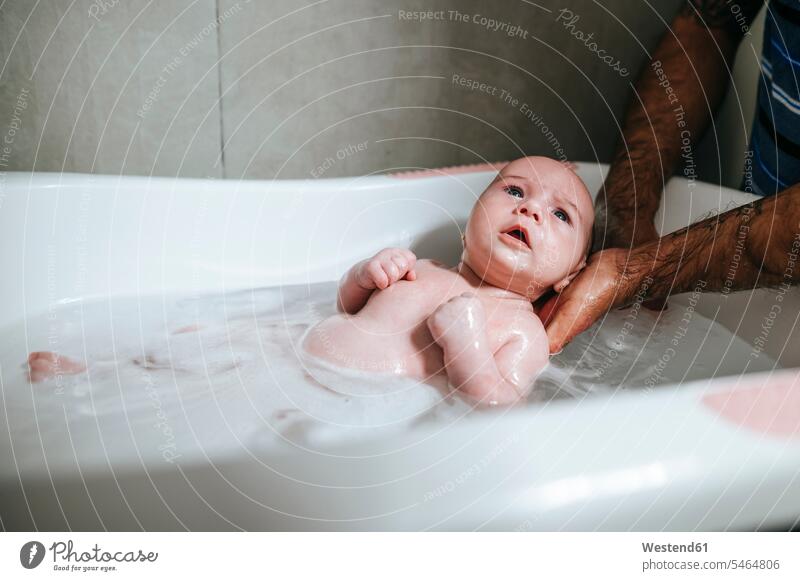 Baby girl bathing, holding by father's hands bath tub bath tubs bathtubs bathe Taking A Bath clean wash wetness hygienic Hygienics community look looks