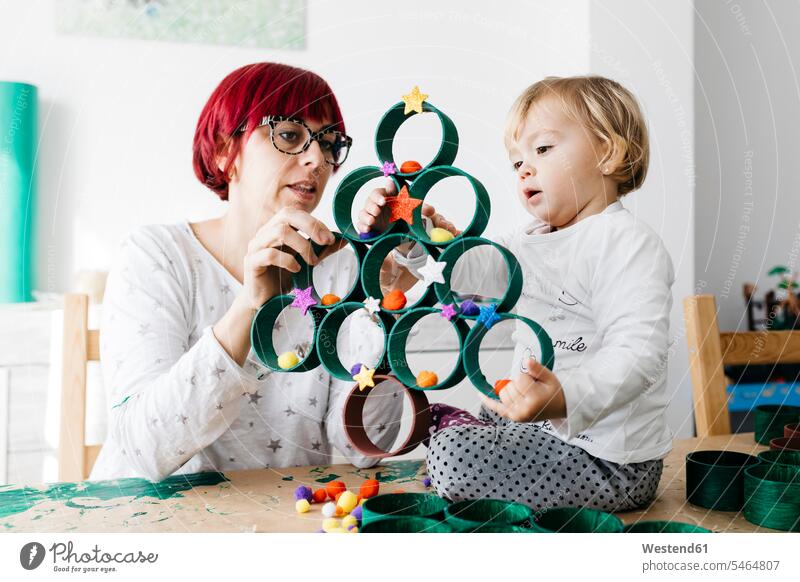Mother and daughter doing crafts at home with accessories to make a Christmas tree human human being human beings humans person persons caucasian appearance