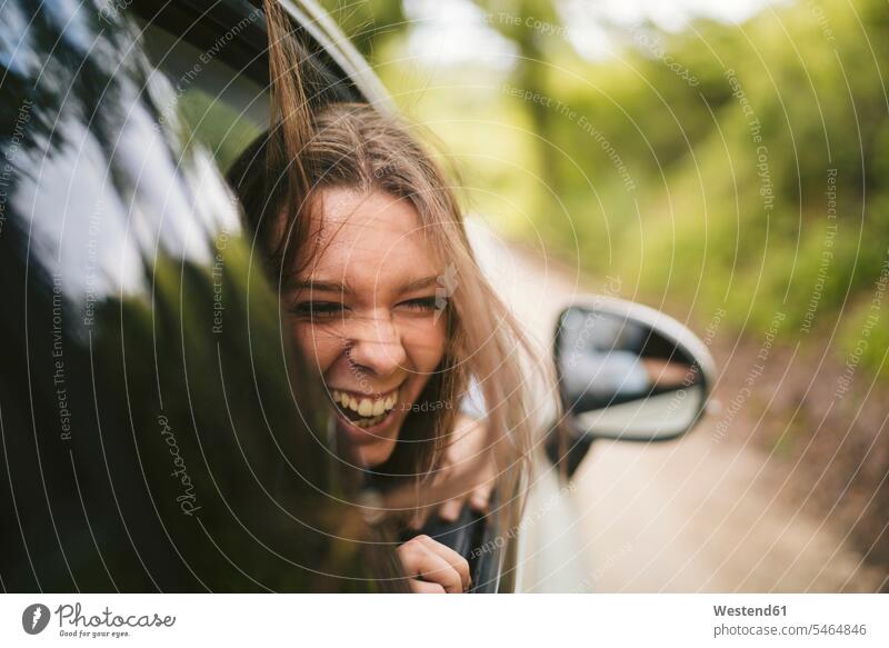 Carefree young woman leaning out of car window motor vehicles road vehicle road vehicles Auto automobile Automobiles cars motorcar motorcars drive motoring