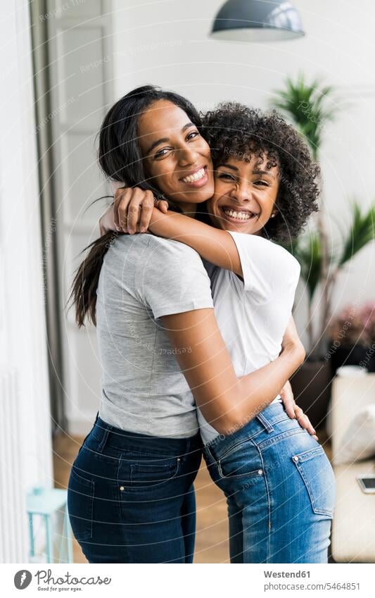 Portrait of two happy girlfriends hugging at home portrait portraits woman females women embracing embrace Embracement female friends happiness Adults grown-ups