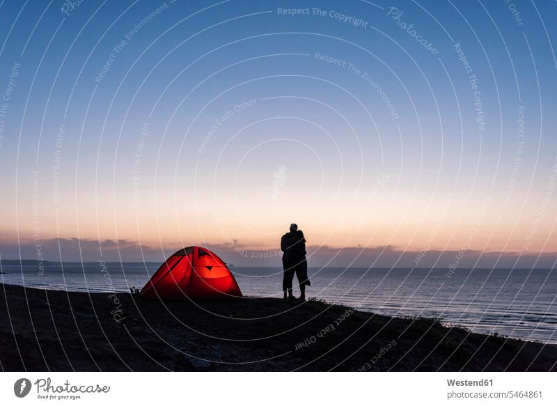 Romantic couple camping on the beach, kissing in twilight beaches twosomes partnership couples embracing embrace Embracement hug hugging kisses people persons