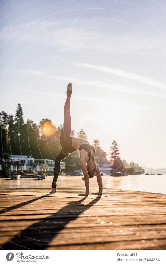 Woman practicing yoga on jetty at a lake jetties lakes Yoga exercise exercises woman females women water waters body of water Adults grown-ups grownups adult