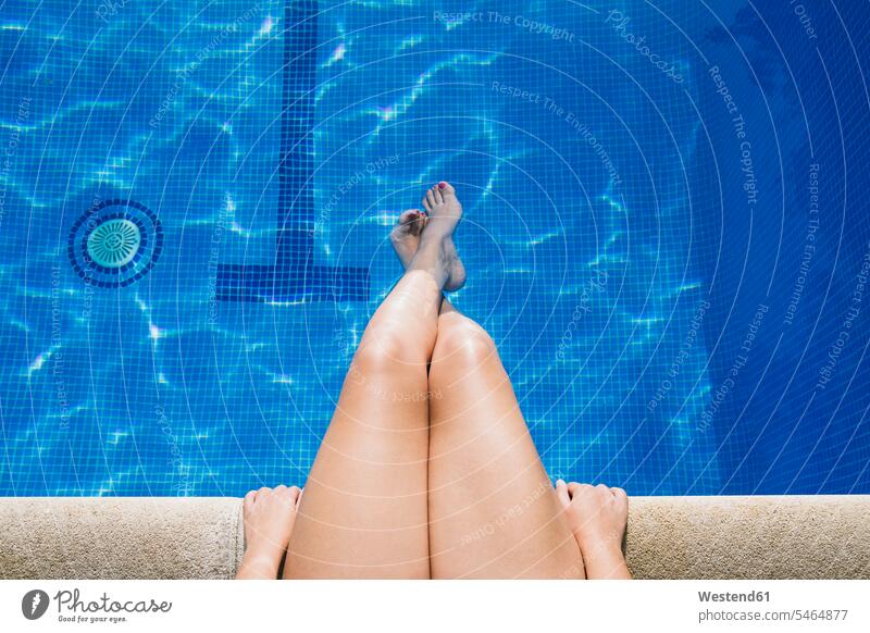 Young woman with feet in water relaxing at poolside color image colour image Spain day daylight shot daylight shots day shots daytime summer summertime