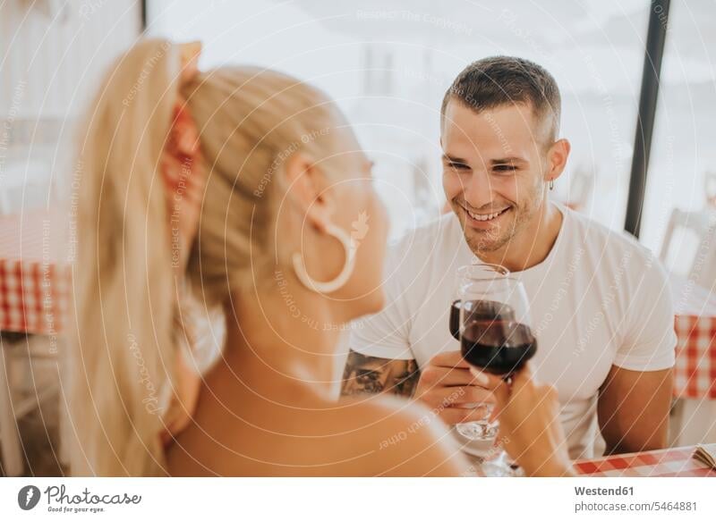 Happy young couple toasting wineglasses in restaurant color image colour image Spain leisure activity leisure activities free time leisure time casual clothing