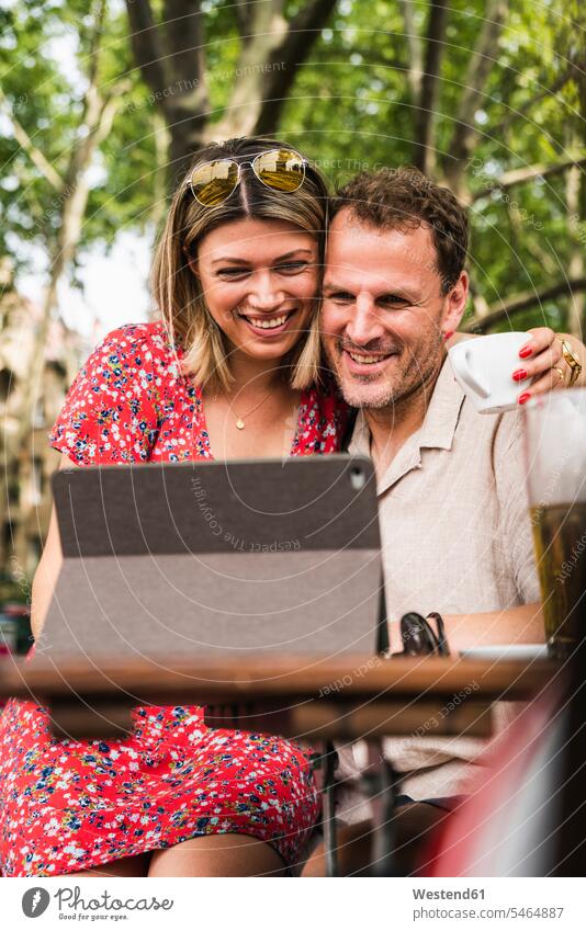 Smiling couple sharing tablet at an outdoor cafe share digitizer Tablet Computer Tablet PC Tablet Computers iPad Digital Tablet digital tablets smiling smile