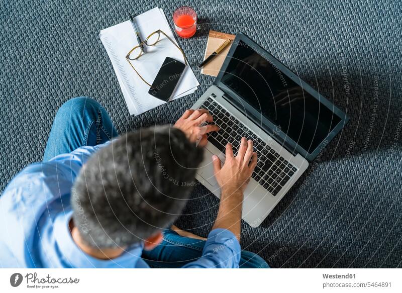 Man sitting on the floor at home using laptop, top view human human being human beings humans person persons caucasian appearance caucasian ethnicity european 1
