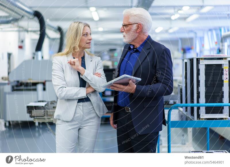Confident businesswoman and businessman looking at each other while discussing in factory color image colour image indoors indoor shot indoor shots interior