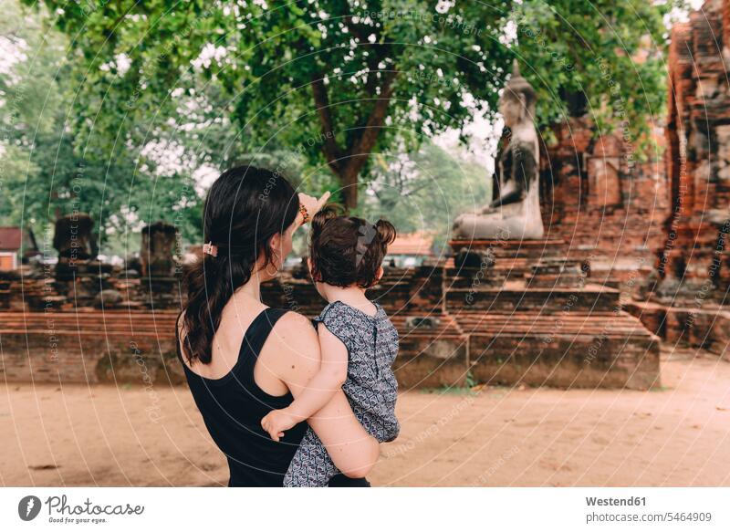 Thailand, Ayutthaya, Mother and daughter looking at a Buddha statue at Wat Mahathat eyeing Buddha figure Buddha figures Buddha statues daughters mother mommy